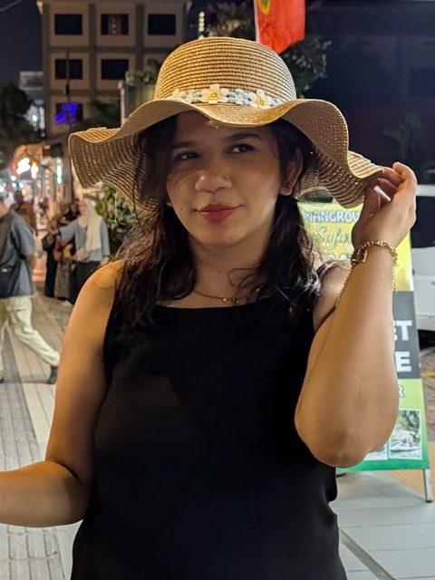 Maheen Chaudhry in a sun hat on an evening street
